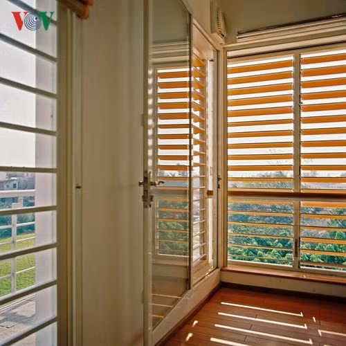 Hệ chớp lật được thiết kế và thi công… thủ công với khung thép và cấu kiện của hệ chớp lật nhôm – kính, nhưng lá chớp được thay bằng gỗ. Hệ chớp cho phép điều chỉnh độ nghiêng để “lọc sáng”. Bên trong là cửa kính để có thể đóng lại khi cần thiết.