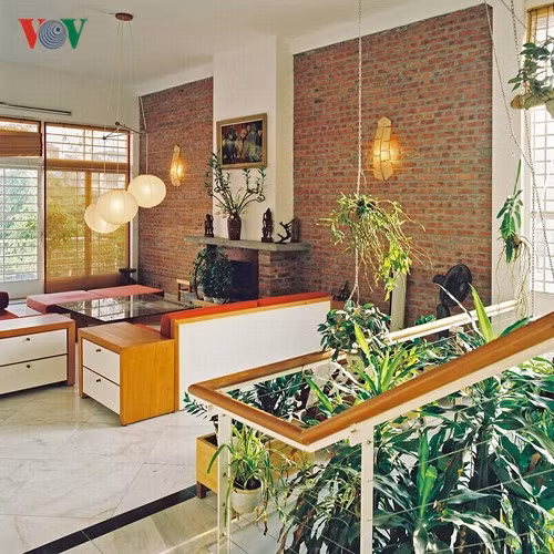 Góc nhìn từ cầu thang về phòng sinh hoạt chung. Phong cách nội thất khá đơn giản, kết hợp của hai yếu tố thô mộc và thanh lịch được thể hiện qua những mảng gạch trần và sắc trắng của tường.