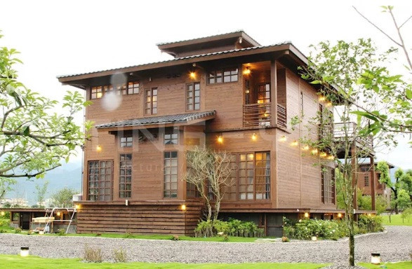 Nhà hình hộp thiết kế theo phong cách hiện đại được bao quanh bởi cây cối và một khu vườn phía trước. 