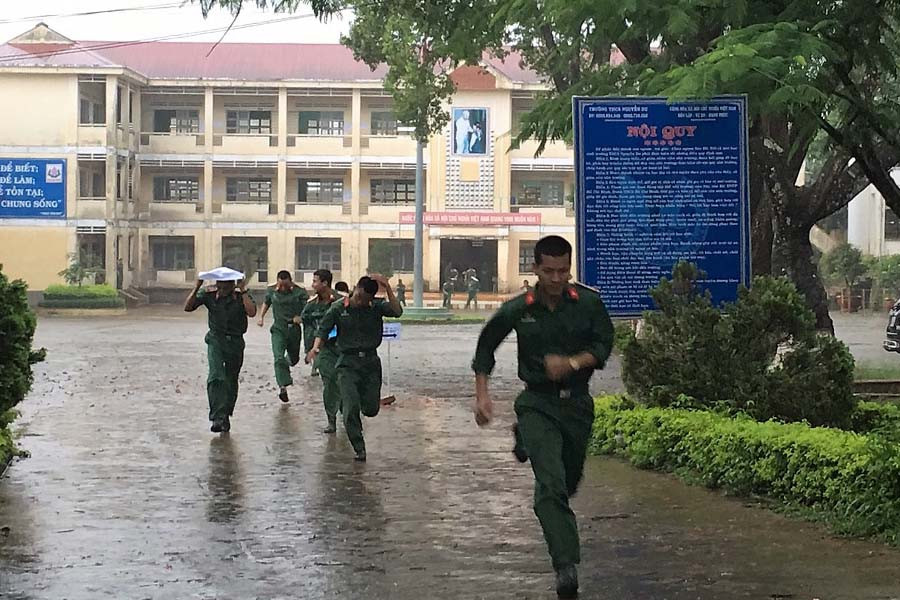 Thí sinh tự do vội vã ra về dưới trời mưa sau khi hoàn thành kỳ thi. Ảnh: Hà Duy