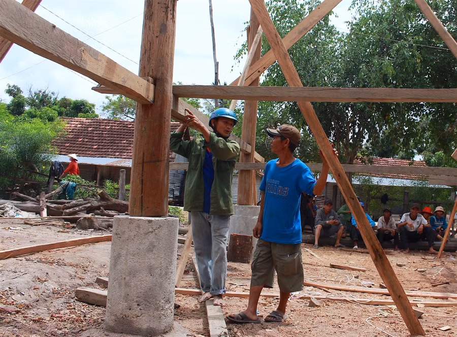 Ông Đinh Tha (bìa phải) trao đổi với thợ để hoàn thiện ngôi nhà mới. Ảnh: Hồng Thi