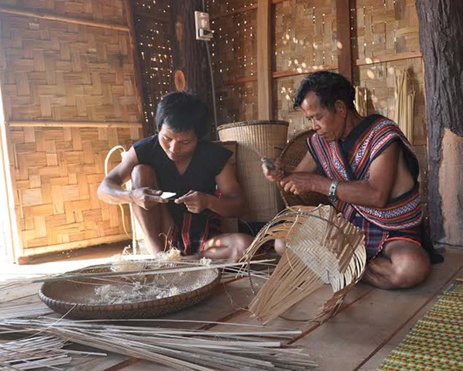 Ông Đinh Ngơn dạy đan gùi cho thanh niên người Bahnar. Ảnh: Hà Duyệt