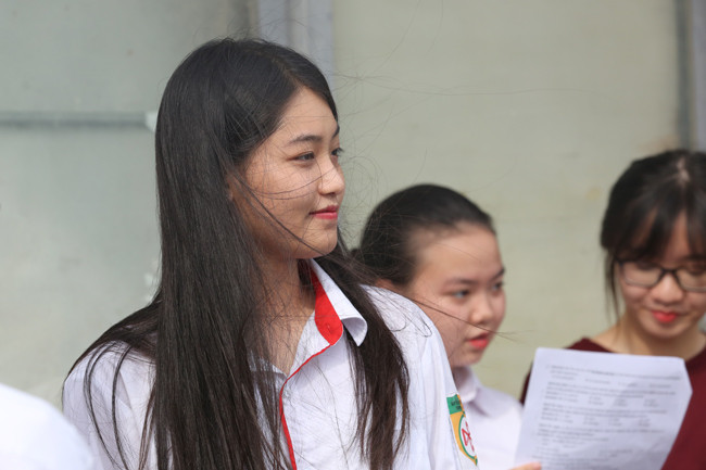 Một nữ sinh kết thúc môn thi Ngoại ngữ đang chờ người thân tới đón.