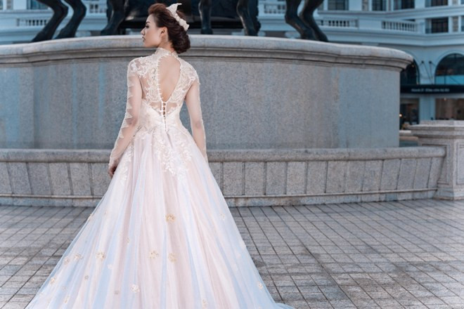 Điểm nhấn của chiếc váy là họa tiết ren đính trên nền voan và phần đuôi váy dài.