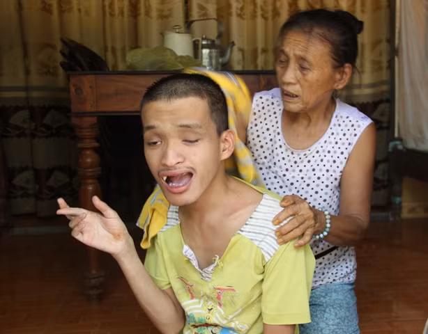 Bà Lê Thị Mít chăm sóc cho đứa con trai bị tàn tật.