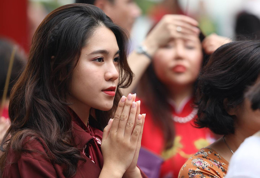 Cô gái trẻ chắp tay thành kính tại sân đền.