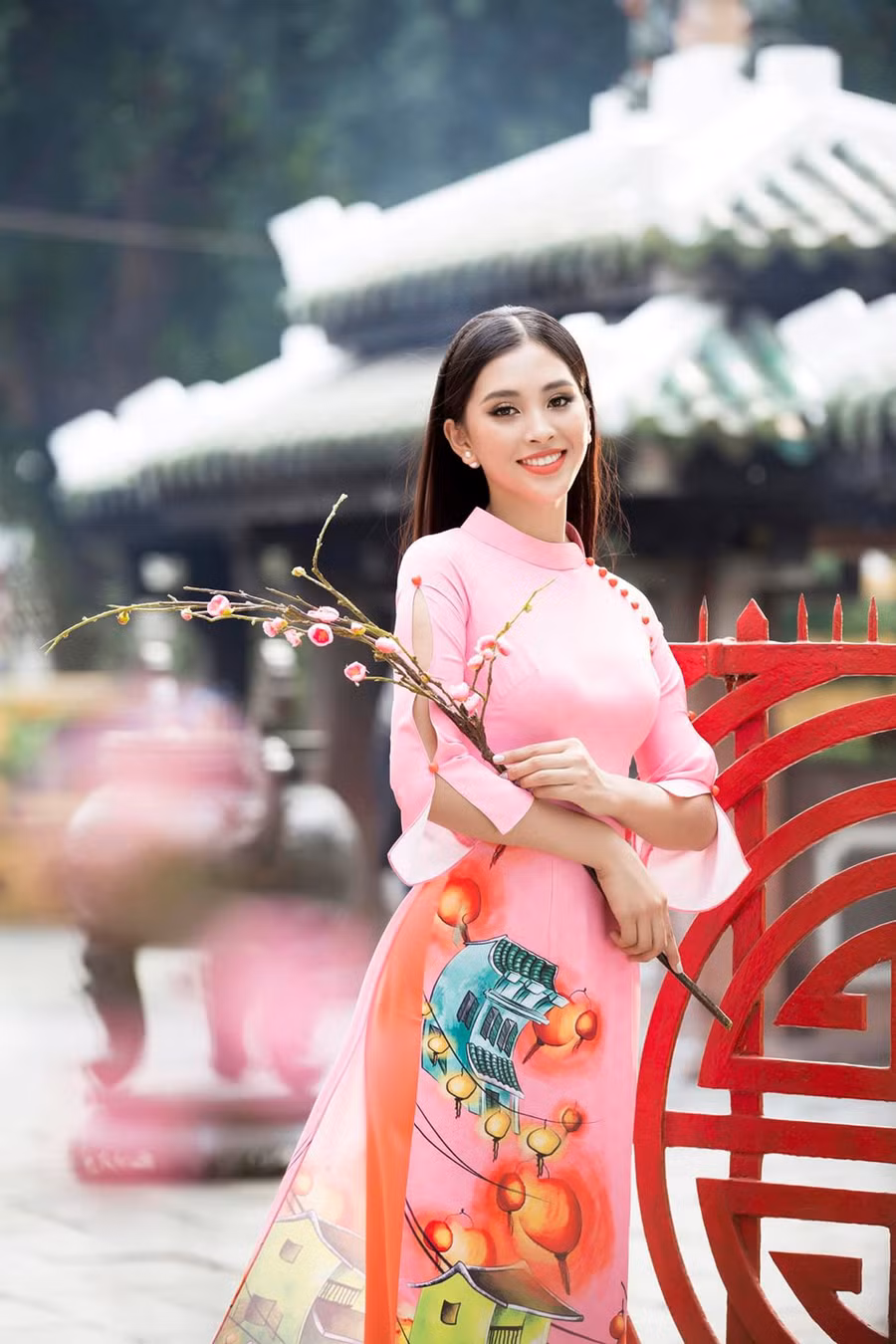  Hoa hậu Tiểu Vy thực hiện bộ ảnh áo dài Tết với những họa tiết của quê nhà Hội An: đèn lồng, phố cổ và những vách mái ngói, cành đào, cành mai. Bộ áo dài có phong cách truyền thống, kết hợp với lối trang điểm truyền thống.