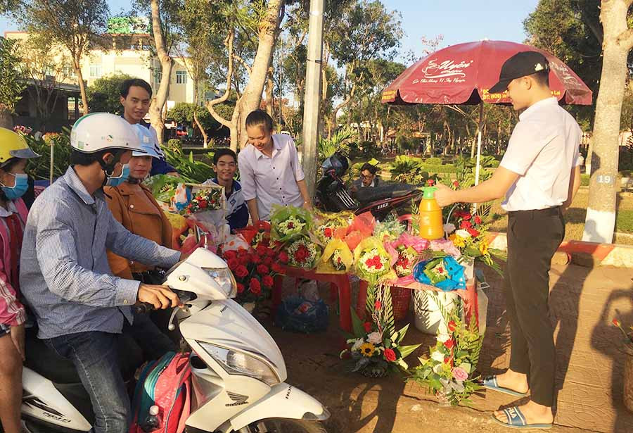  Các thành viên trong CLB “Vòng tay yêu thương” bán hoa gây quỹ. Ảnh: N.T