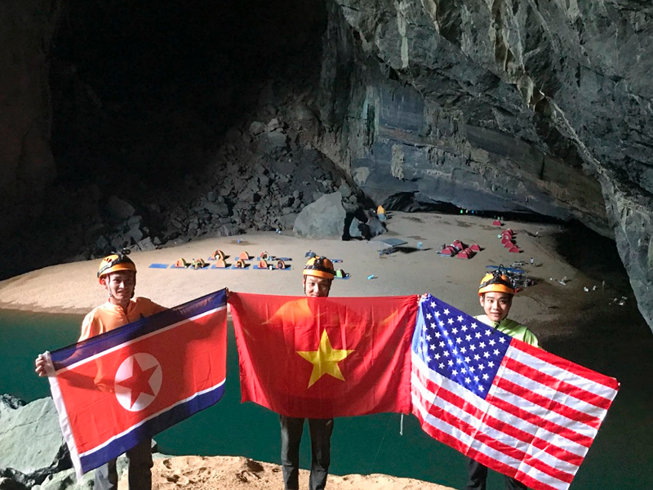  Một nhóm thám hiểm hang động Sơn Đoòng ở tỉnh Quảng Bình giơ cao các lá cờ CHDCND Triều Tiên, Việt Nam và Mỹ (từ trái sang), chào mừng sự kiện cuộc gặp thượng đỉnh Mỹ-Triều sẽ diễn ra tại thủ đô Hà Nội vào ngày 27 và 28-2. Ảnh: AP