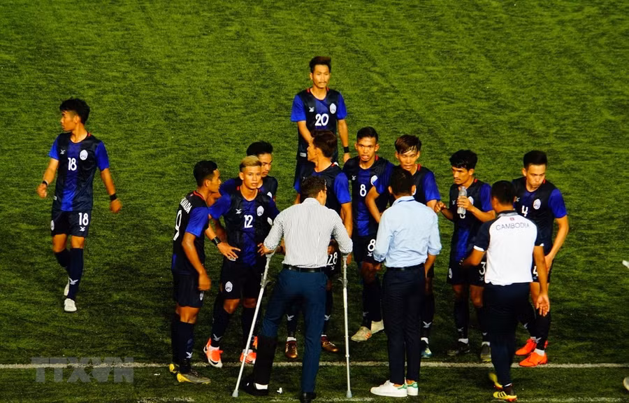  Huấn luyện viên U22 Campuchia (chống nạng) chỉ đạo các cầu thủ. (Ảnh: TTXVN) 