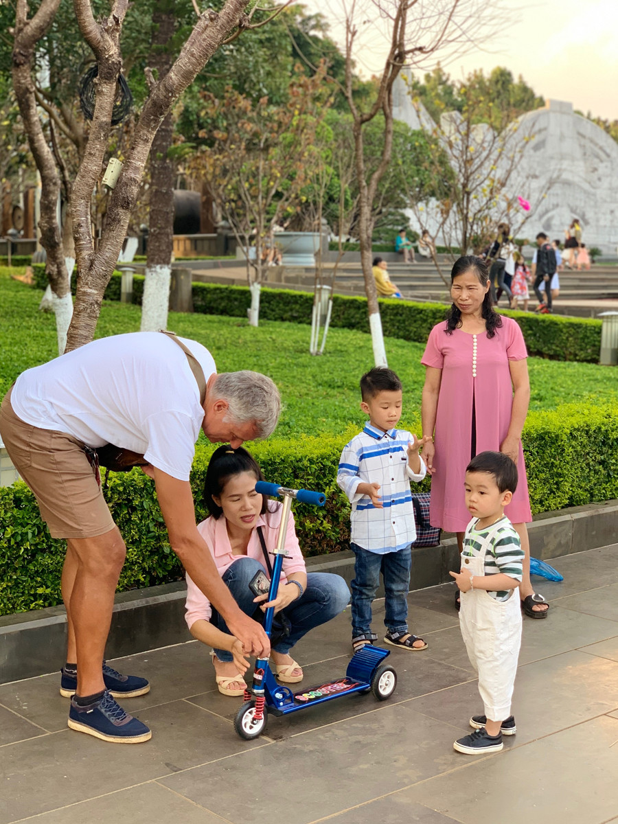 Ông Eddy giúp sửa xe scooter cho các em nhỏ trong lúc đang dạo chơi tại Quảng trường Đại Đoàn Kết. Ảnh: P.V