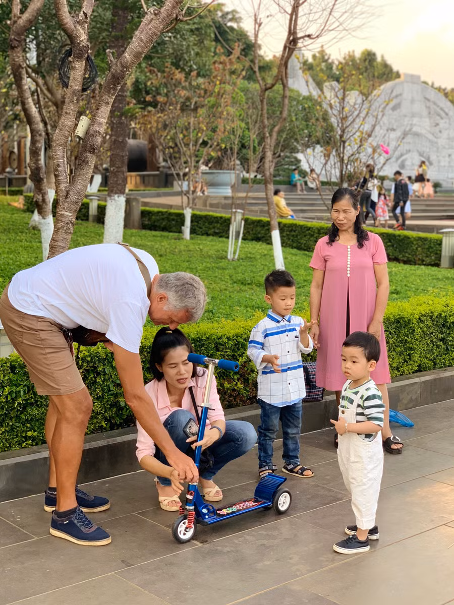 Ông Eddy giúp sửa xe scooter cho các em nhỏ trong lúc đang dạo chơi tại Quảng trường Đại Đoàn Kết. Ảnh: P.V