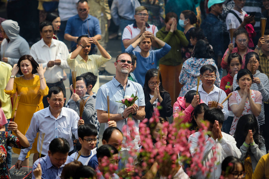 Do lượng người quá đông, Ban quản lý chùa đề nghị mỗi người chỉ thắp một đến ba cây nhang để tránh bị ngạt, hoả hoạn. Trong ảnh, Phật tử người nước ngoài mang hoa sen - biểu tượng của Phật giáo, đến cầu may mắn đầu năm.