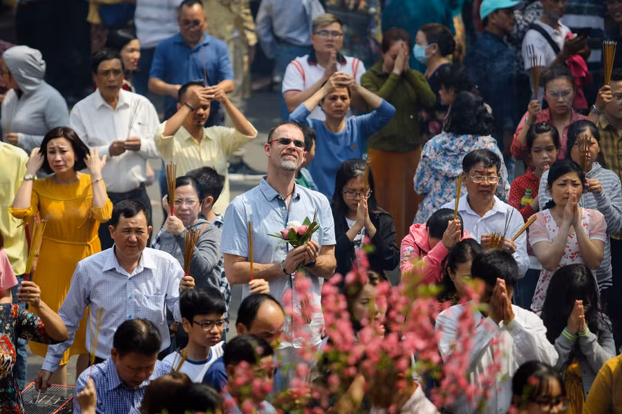 Do lượng người quá đông, Ban quản lý chùa đề nghị mỗi người chỉ thắp một đến ba cây nhang để tránh bị ngạt, hoả hoạn. Trong ảnh, Phật tử người nước ngoài mang hoa sen - biểu tượng của Phật giáo, đến cầu may mắn đầu năm.