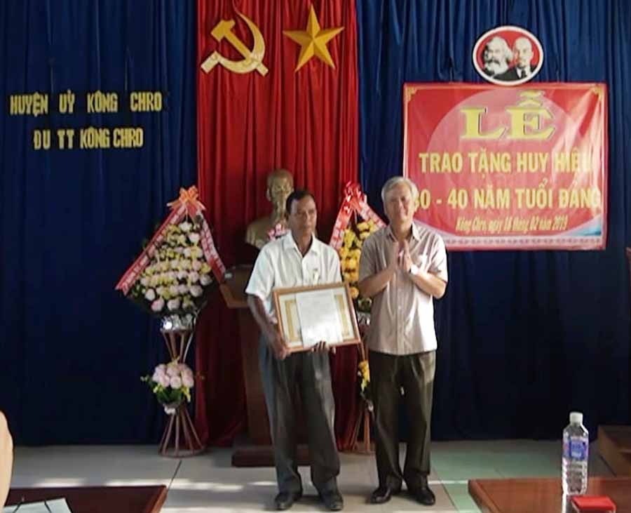  Đồng chí Trần Cao Nguyên-Tỉnh ủy viên, Bí thư huyện ủy trao Huy hiệu 40 năm tuổi Đảng cho đảng viên Đinh Keo thuộc Đảng ủy thị trấn Kông Chro. Ảnh: Thúy Ngọ