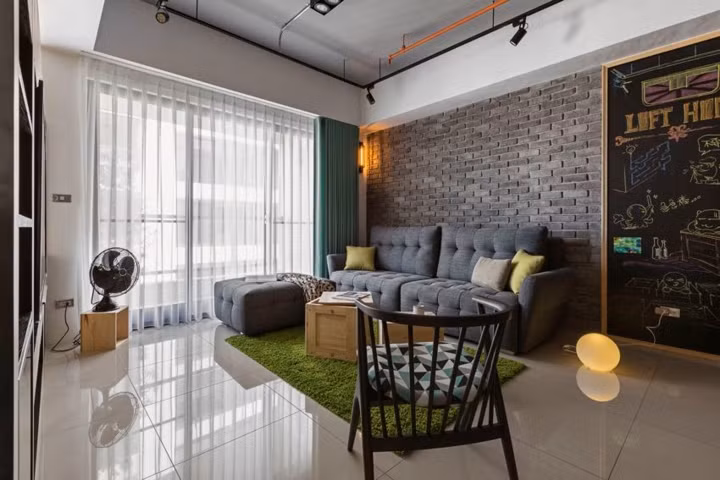 Sàn nhà bằng gạch men bóng loáng tăng diện tích, một chiếc thảm màu xanh đóng khung khu vực tiếp khách.