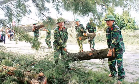 Cán bộ chiến sĩ Huyện đội Cẩm Xuyên dọn dẹp cây xanh bị bão quật ngã để đảm bảo an toàn giao thông.