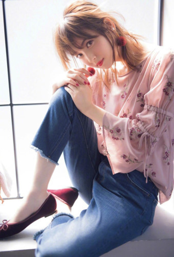  Người đẹp 29 tuổi diện quần jeans và áo hoa, đeo bông tai cùng tông màu son môi, sơn móng tay.