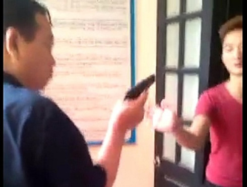 Người đàn ông được cho là ông Lê Quang Sơn cầm vật giống khẩu súng chĩa vào người khác. (Ảnh cắt từ clip). Người đàn ông được cho là ông Lê Quang Sơn cầm vật giống khẩu súng chĩa vào người khác. (Ảnh cắt từ clip).