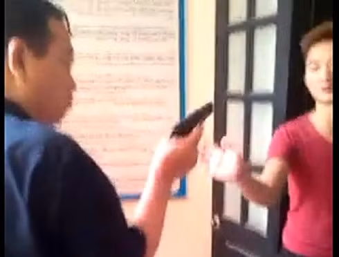 Người đàn ông được cho là ông Lê Quang Sơn cầm vật giống khẩu súng chĩa vào người khác. (Ảnh cắt từ clip). Người đàn ông được cho là ông Lê Quang Sơn cầm vật giống khẩu súng chĩa vào người khác. (Ảnh cắt từ clip).