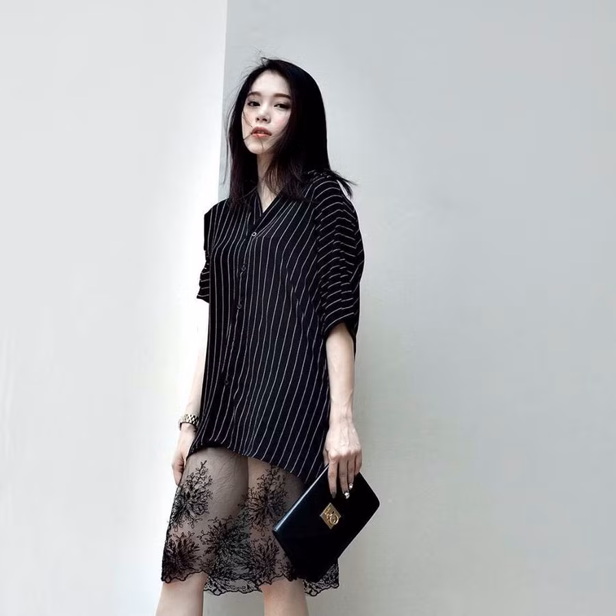 Ngô Phương Linh chia sẻ bí quyết thể hiện hình ảnh một tiểu thư gợi cảm, sành điệu khi kết hợp phá cách chiếc áo sơ mi kẻ sọc phom dáng dài, cùng chân váy ren xuyên thấu và túi xách cầm tay đơn giản.