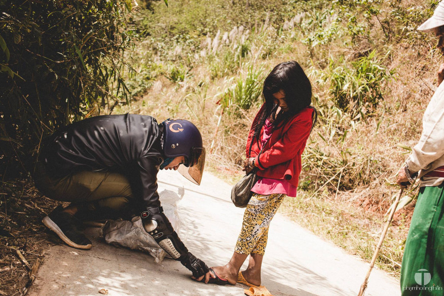  Một bé gái bẽn lẽn khi được anh chàng phượt thủ ướm đôi dép mới - Ảnh: P.H.T