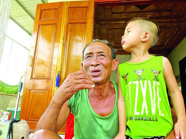 Ông Nguyễn Lạc cùng đứa cháu tại căn nhà của mình, nơi đêm trước đã cưu mang hàng chục người dân trú bão.