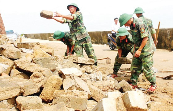 Cán bộ chiến sĩ Huyện đội Cẩm Xuyên, tỉnh Hà Tĩnh giúp các hộ dân ở xã Cẩm Nhượng dọn dẹp tường rào.