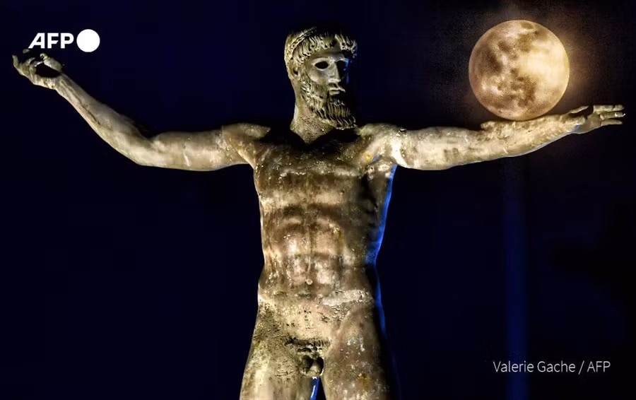 Trăng rằm xuất hiện đằng sau bức tượng điêu khắc Thần Biển Peseidon, tại Corinth, Hy Lạp. Ảnh: AFP