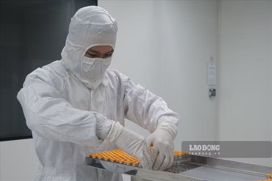 Nhân viên kỹ thuật đang siết nắp nhôm, một công đoạn để sản xuất vaccine Nanocovax ngừa COVID-19. Ảnh: Thanh Chân