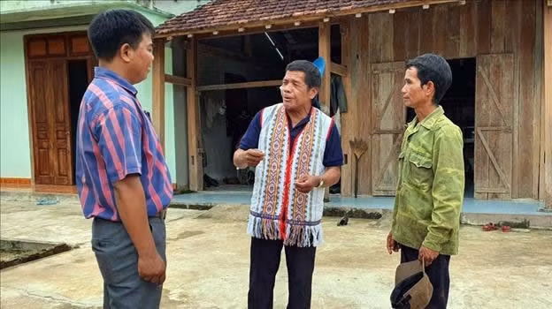 Ông A Blong (giữa) cùng đại diện chính quyền địa phương tuyên truyền đến các hộ dân về chính sách mới.