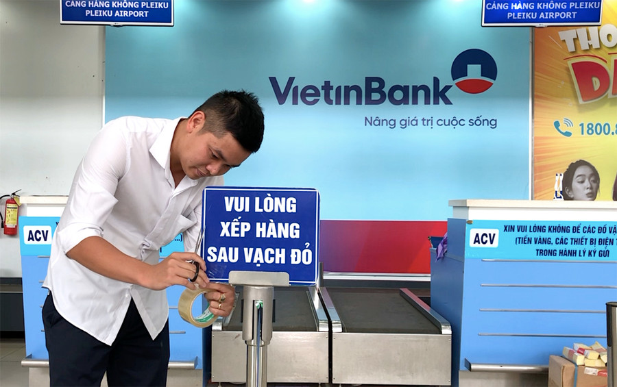 Nhân viên Cảng Hàng không Pleiku gắn các vị trí để hành khách đứng giữ khoảng cách tại khu vực quầy check-in. Ảnh: Lê Hòa Nhân viên Cảng Hàng không Pleiku gắn các vị trí để hành khách đứng giữ khoảng cách tại khu vực quầy check-in. Ảnh: Lê Hòa
