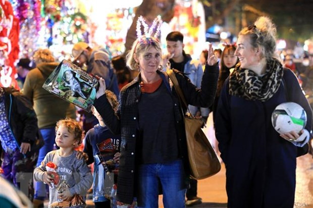 Trên phố Hàng Mã, những người ngoại quốc đang sinh sống tại Việt Nam đi mua sắm đồ chuẩn bị đón Noel. (Ảnh: Thành Đạt/TTXVN)