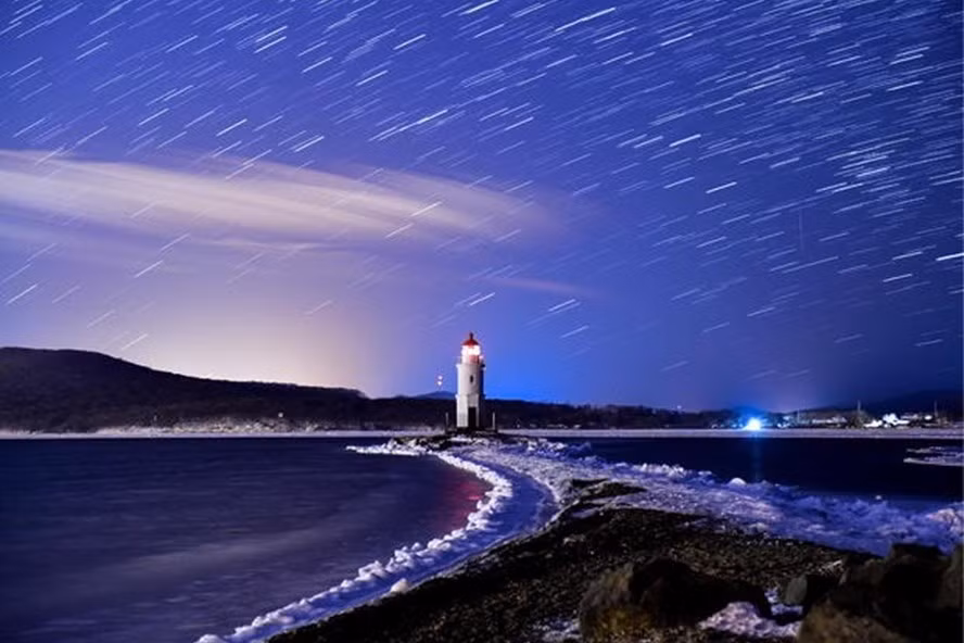 Mưa sao băng Geminids khi đạt cực điểm trên bầu trời đêm trên ngọn hải đăng Tokarevsky ở mũi Egersheld trên đảo Russky ở biển Nhật Bản vào ngày 13 tháng 12 năm 2017. Ảnh: Getty Images.