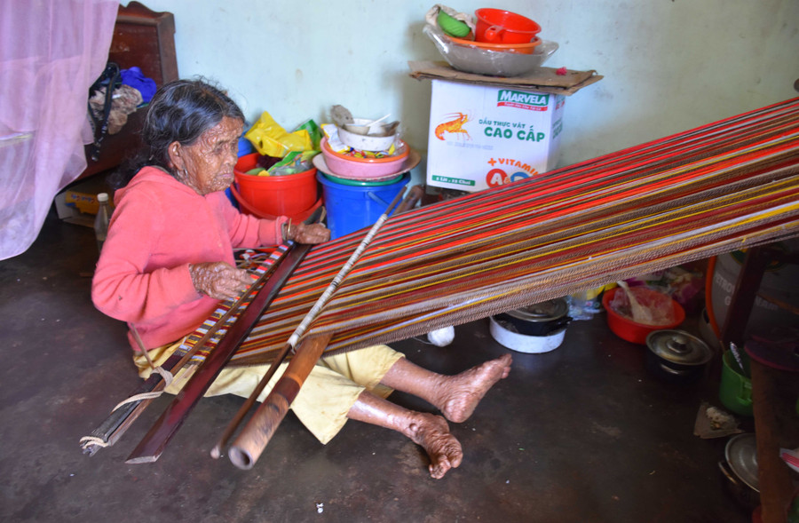 Bà Rơ Châm Bô đang ngồi dệt lụa trong căn phòng của mình. Ảnh: Hà Phương