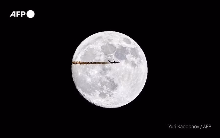 Máy bay bay ngang qua hình ảnh mặt trăng trong ngày trăng rằm ở Mátxcơva, Nga. Ảnh: AFP
