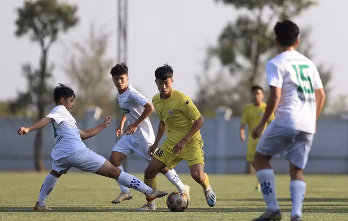 U17 Hà Nội (áo vàng) trong vòng vây các cầu thủ của Học viện Nutifood