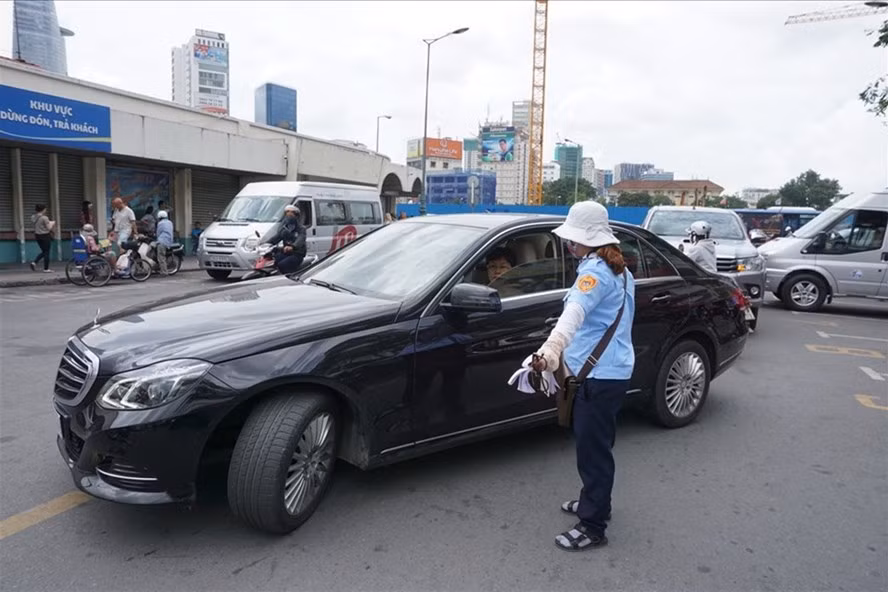  Nhân viên thu phí hướng dẫn cho xe ôtô vào đậu tại điểm đỗ xe ôtô có thu phí trên đường Phan Bội Châu (Q.1, TPHCM). Ảnh: MINH QUÂN