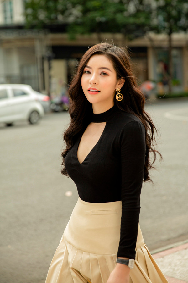 Chân váy xòe tông màu trung tính được tạo điểm nhấn bằng những nếp gấp tinh tế. Trang phục đi kèm là áo thun ôm với chi tiết cut-out phần ngực áo.
