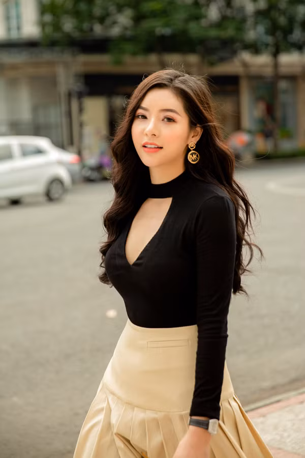 Chân váy xòe tông màu trung tính được tạo điểm nhấn bằng những nếp gấp tinh tế. Trang phục đi kèm là áo thun ôm với chi tiết cut-out phần ngực áo.