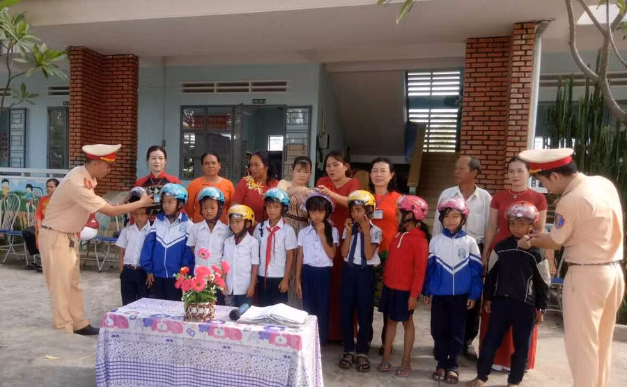 Trao mũ bảo hiểm cho các em học sinh giỏi có hoàn cảnh khó khăn. Ảnh: Yến Lê