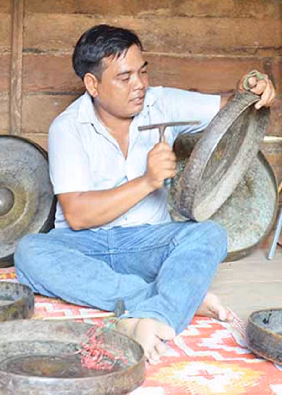  Anh Grinh đang chỉnh chiêng ở nhà rông làng Klah (xã Kon Chiêng). Ảnh: L.A