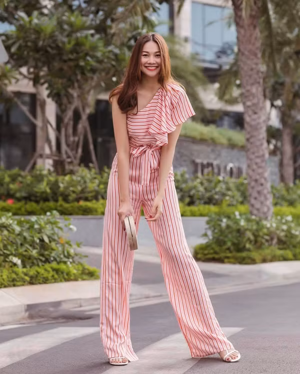  Vốn là một 'tín đồ' skinny, nhưng Thanh Hằng cũng không thể bỏ qua 'cơn sốt' quần suông ống rộng thịnh hành ở mùa mốt năm nay. Siêu mẫu làm mới phong cách street style với trang phục áo liền quần trên chất liệu kẻ sọc màu sắc tươi sáng.