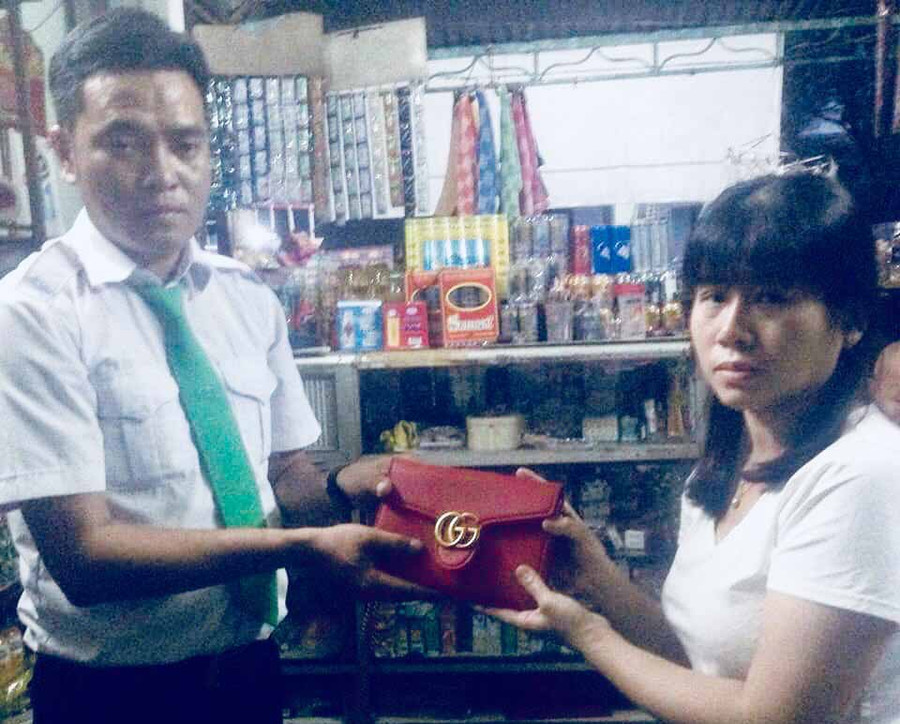 Tài xế Nguyễn Minh Vương trao lại chiếc túi xách cho người thân chủ nhân nhân chiếc túi bỏ quên. Ảnh: Lê Hoà.