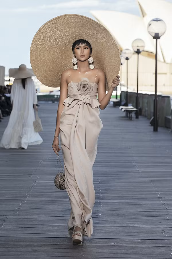 H'Hen Niê trong một thiết kế với chất liệu linen do Đỗ Mạnh Cường lăng xê. Dù đội chiếc mũ cói rộng vành, cô vẫn rất khéo léo trong màn trình diễn.