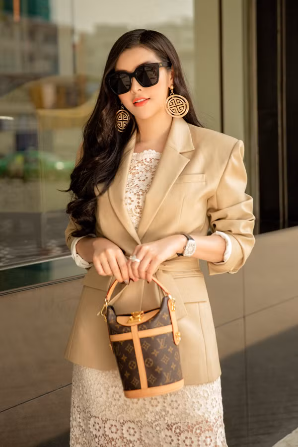 Mẫu áo khoác tạo nên điểm nhấn cuốn hút cho tổng thể nhờ tông màu cà phê sữa hợp mốt và phom dáng độc đáo bởi phần vai to bản, thắt eo điệu đà.