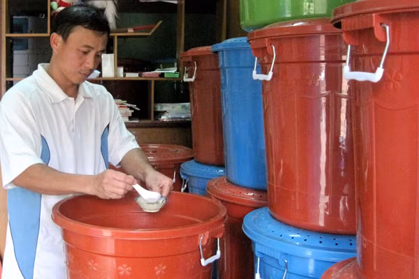 Anh Phạm Thế Chính bổ sung thức ăn và nước uống cho dế. Ảnh: Hồng Thi.