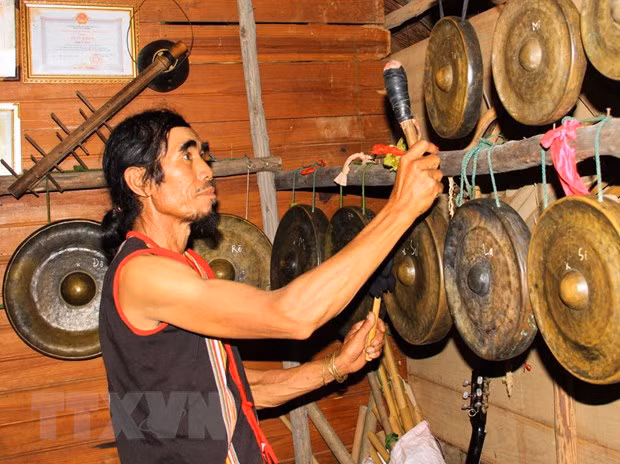 Ông A Thui thử âm của những bộ cồng chiêng. (Ảnh: Khoa Chương/TTXVN)