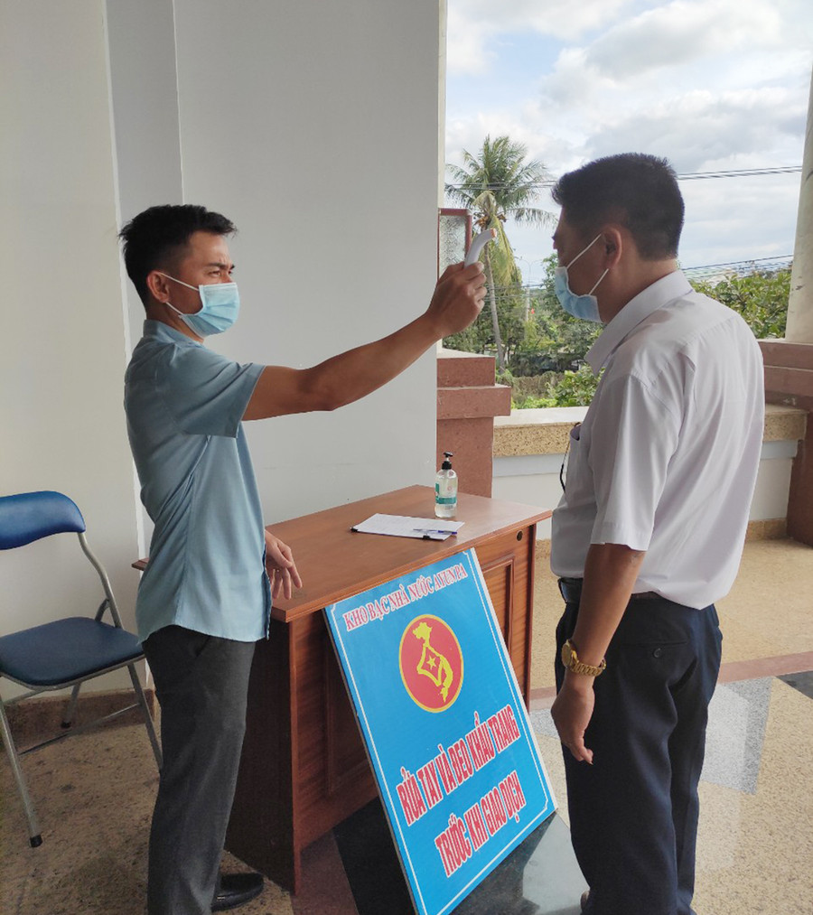  Kho bạc Nhà nước thị xã Ayun Pa thực hiện đo thân nhiệt, sát khuẩn và kiểm tra thông tin đối với khách hàng đến giao dịch, liên hệ công tác. Ảnh: Sơn Ca