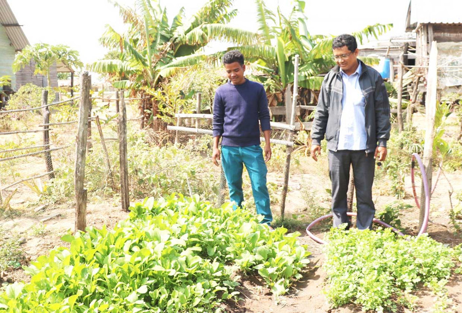 Anh Đinh Byei (bên trái) cải tạo đất vườn của gia đình trồng rau để bà con trong làng học hỏi làm theo. Ảnh: Nhật Hào